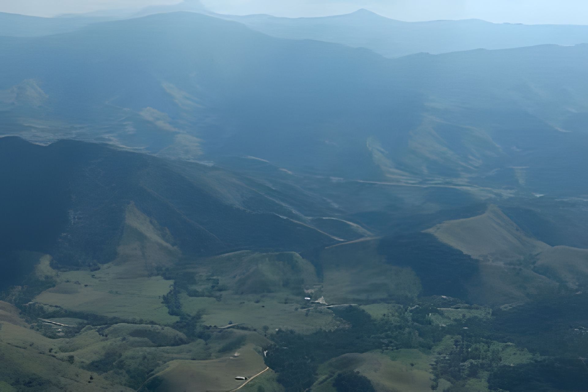 A mountainous landscape with a valley and a small building.
