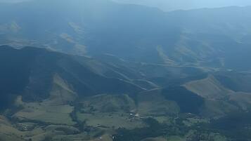 A mountainous landscape with a valley and a small building.