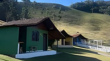 Una hilera de edificios verdes y amarillos con un área verde frente a ellos, ubicados en una ladera.