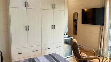 A room with a bed, a wardrobe, a television, and a chair.
