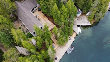 A house with a dock extending into a body of water, surrounded by dense greenery.