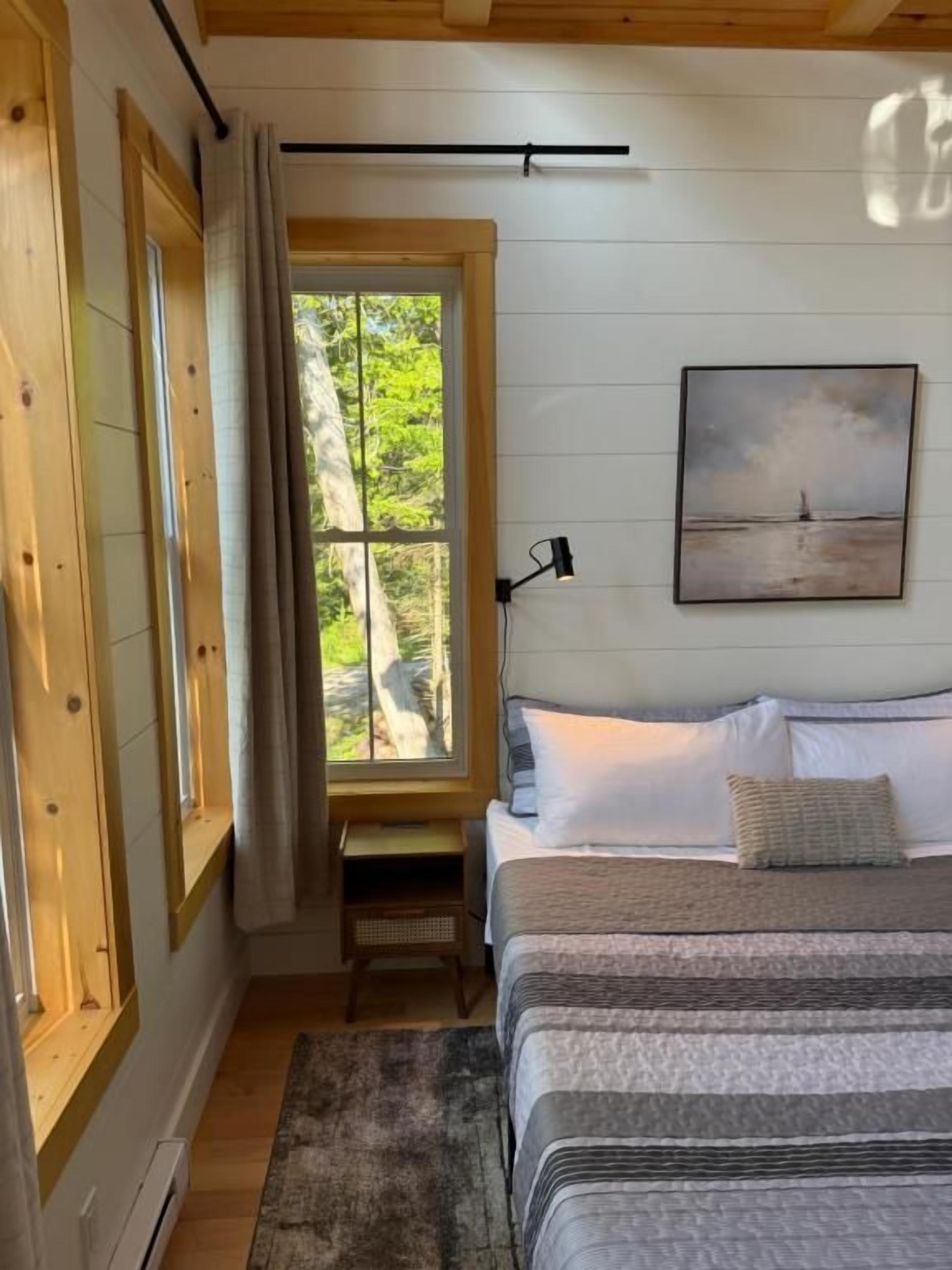 Quarto com cama, janela, quadro e escrivaninha.
