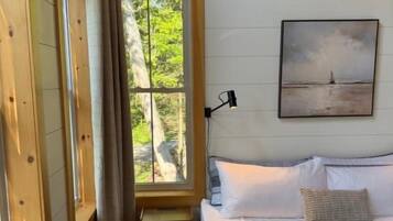 Quarto com cama, janela, quadro e escrivaninha.
