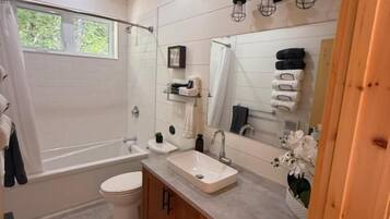 A bathroom with a bathtub, toilet, sink, and wooden cabinets.
