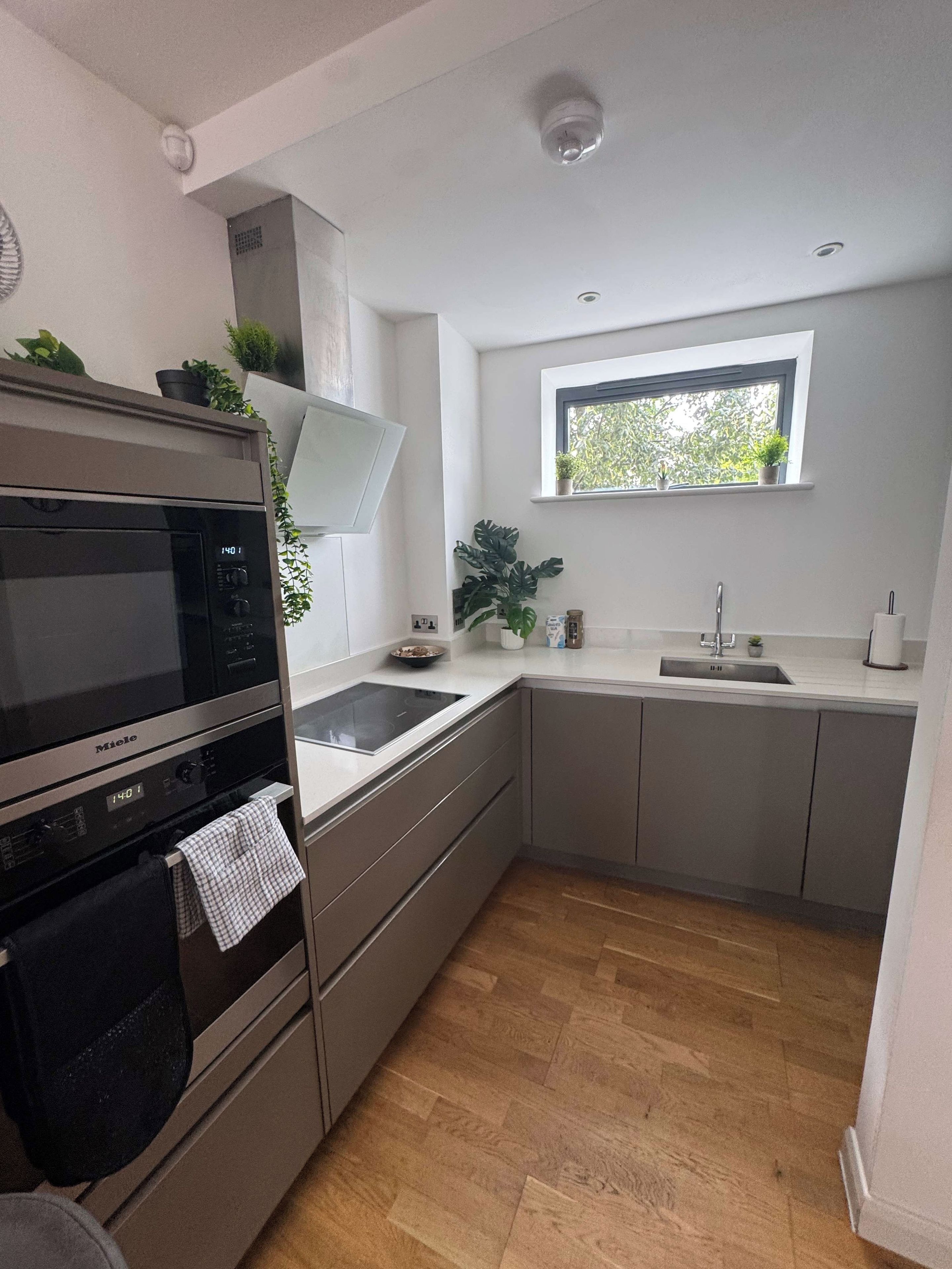 A modern kitchen with a built-in oven, microwave, and a window above the sink.