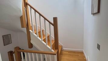 A wooden staircase with white railings leading to a landing.