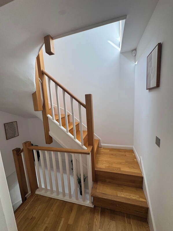 Una escalera de madera con barandillas blancas que da a una plataforma.