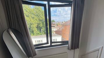 A room with a large window, a radiator, and a mirror leaning against the wall.