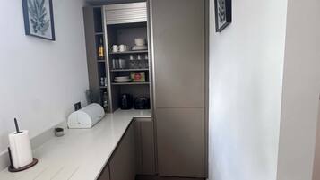 Una cocina pequeña con encimera blanca, horno integrado y suelo de madera.