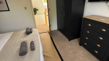 A bedroom with a bed, a wardrobe, a television, and a door leading to another room.