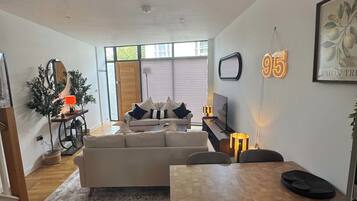 A modern living room with a sofa, a dining table, and a TV.