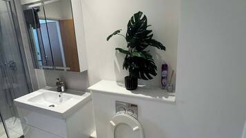 Un bagno moderno con toilette, lavandino e doccia.