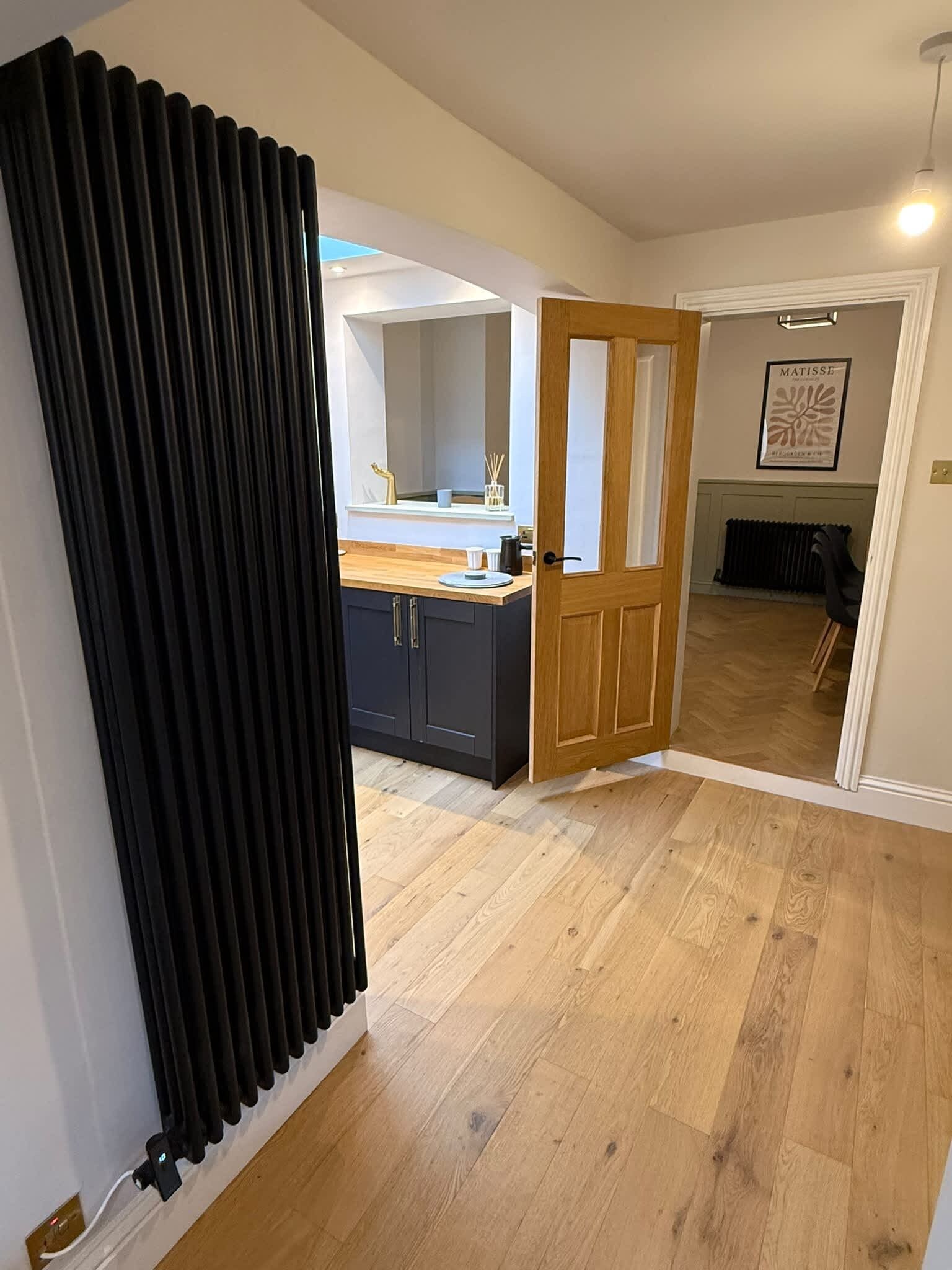 A modern kitchen with dark cabinets, a wooden countertop, and a door leading to a dining area.