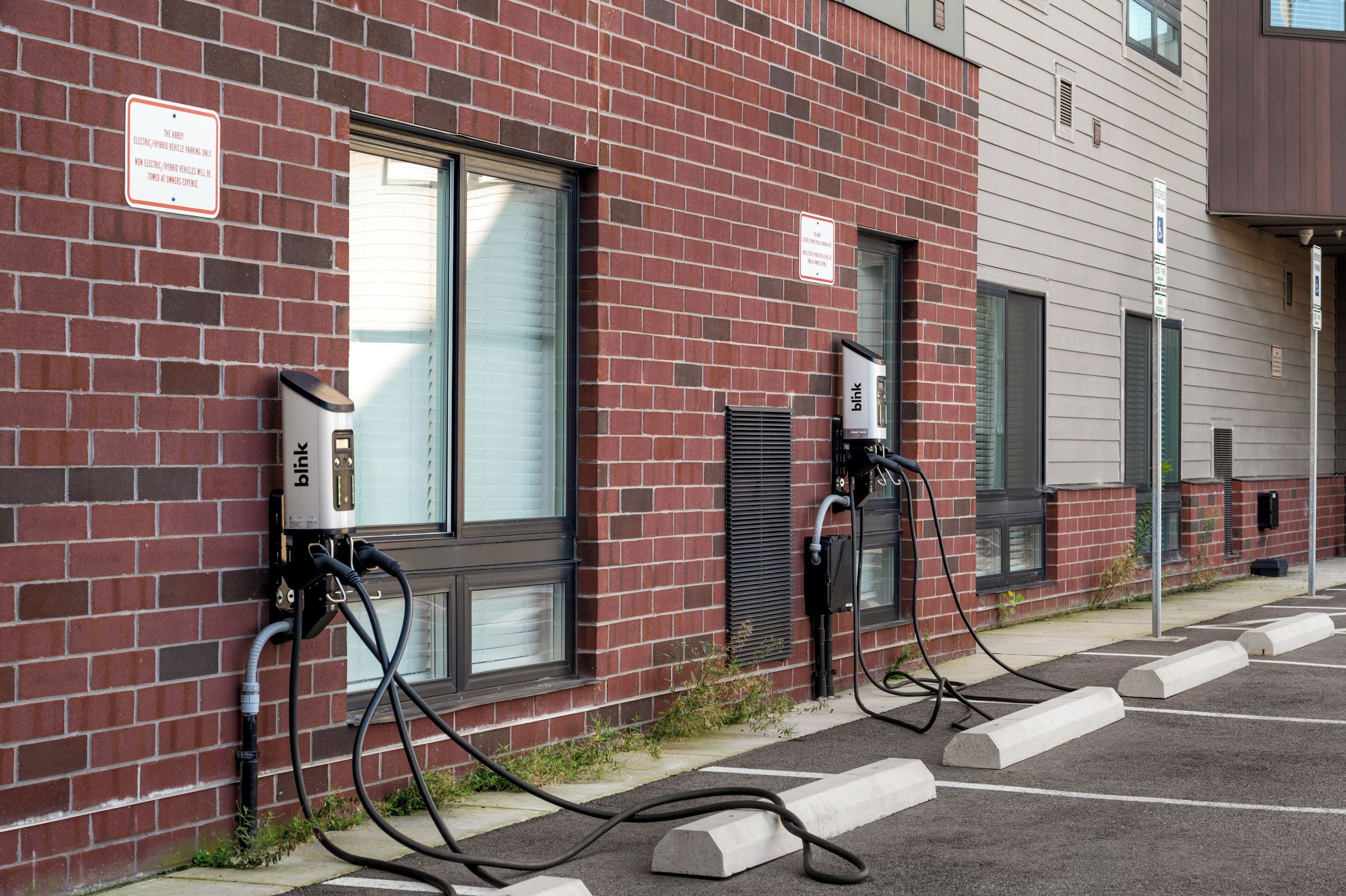 Ein Backsteinhaus mit Ladestationen für Elektrofahrzeuge und einem Parkplatz.