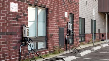 Ein Backsteinhaus mit Ladestationen für Elektrofahrzeuge und einem Parkplatz.