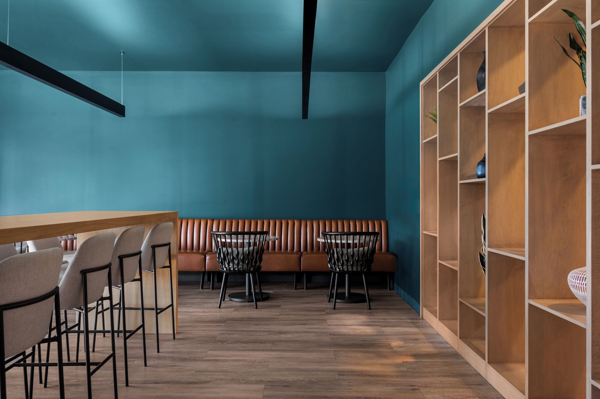 Ein modernes Interieur mit einem Holztisch, zwei Stühlen, einer Bank und einem Bücherregal.