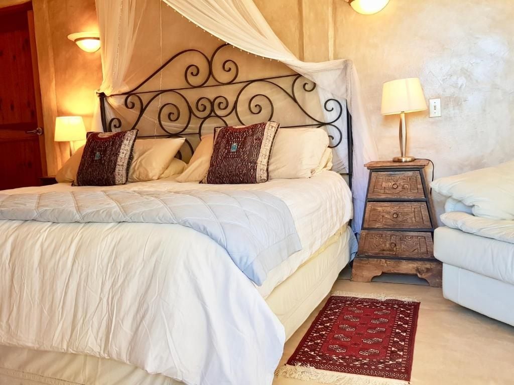 A bedroom with a bed, bedside tables, a nightstand, and a red patterned rug.