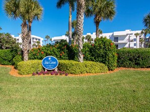 A sign for Sea Cove, a private residence, surrounded by well-maintained landscaping and palm trees.