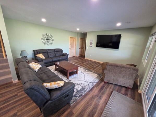 A living room with a sectional sofa, a loveseat, a coffee table, and a flat-screen TV mounted on the wall. - NEW Lakefront Home built 2026, Modern/Rustic, Kayaks & Games, 20 Min to WI Dells (Oxford)