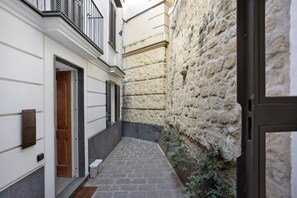 A narrow stone-paved alleyway between buildings with white walls and black shutters. - Residenza Scale Napoletane - Deluxe Double Suite (Napoli)