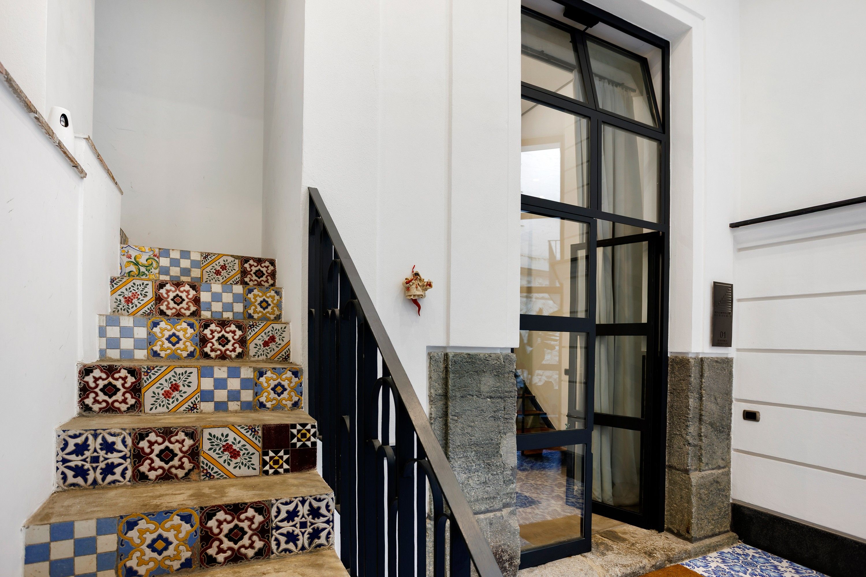 A staircase with colorful patterned tiles leading to a door with a glass panel.