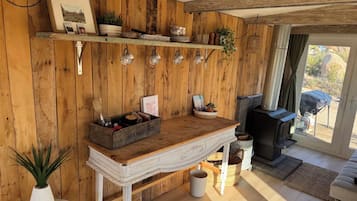 A rustic interior with wooden walls, a fireplace, and a dining area with a wooden table and chairs.