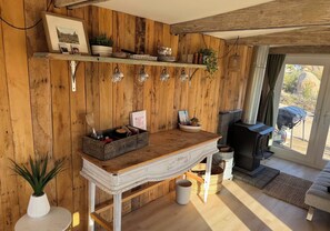 Een rustiek interieur met houten wanden, een open haard en een eethoek met een houten tafel en stoelen.