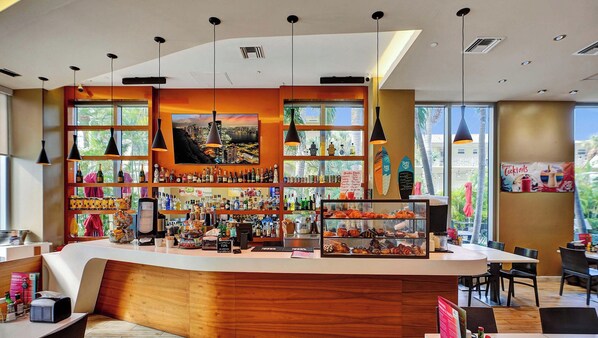 A modern bar with a curved counter, various liquor bottles, and a menu board. - Home‑Style Beachwalk APT  2BR w/ Bay View (Hallandale Beach)