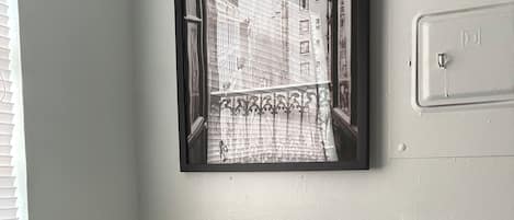 Une cuisine équipée d’un four à micro-ondes, d’une machine à café et d’une photographie encadrée représentant un paysage urbain, accrochée au mur.