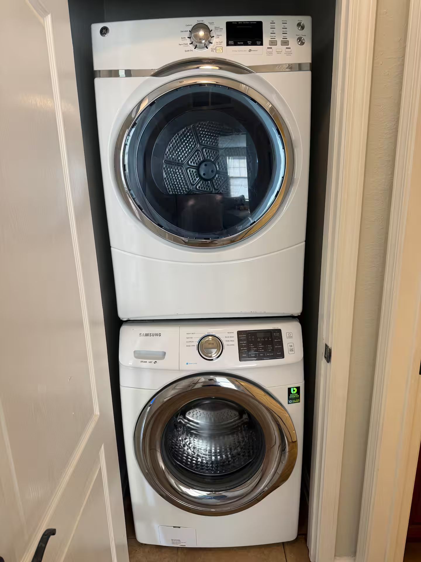 Een gestapelde wasmachine en droger met een digitaal display en bedieningspaneel.