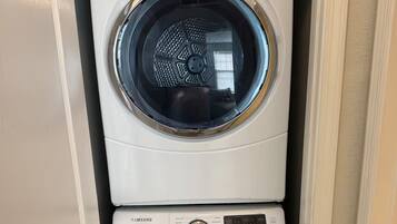 Een gestapelde wasmachine en droger met een digitaal display en bedieningspaneel.