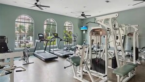 Un gimnàs amb cintes de córrer, aparells de musculació i una pantalla de televisió.