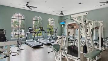 Een fitnessruimte met loopbanden, gewichtstoestellen en een televisiescherm.