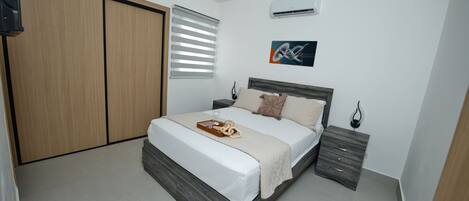A bedroom with a bed, bedside tables, a wardrobe, and an air conditioning unit.