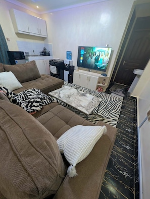 Olohuone, jossa on sohva, sohvapöytä, televisio ja taustalla keittiö.