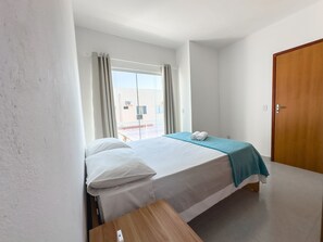 Ein Hotelzimmer mit einem Bett, einem Nachttisch, einem Fenster mit Vorhängen und einer Tür.
