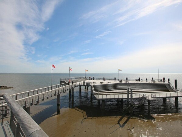 Eine Mole, die sich in ruhiges Wasser erstreckt, mit blauem Himmel darüber.