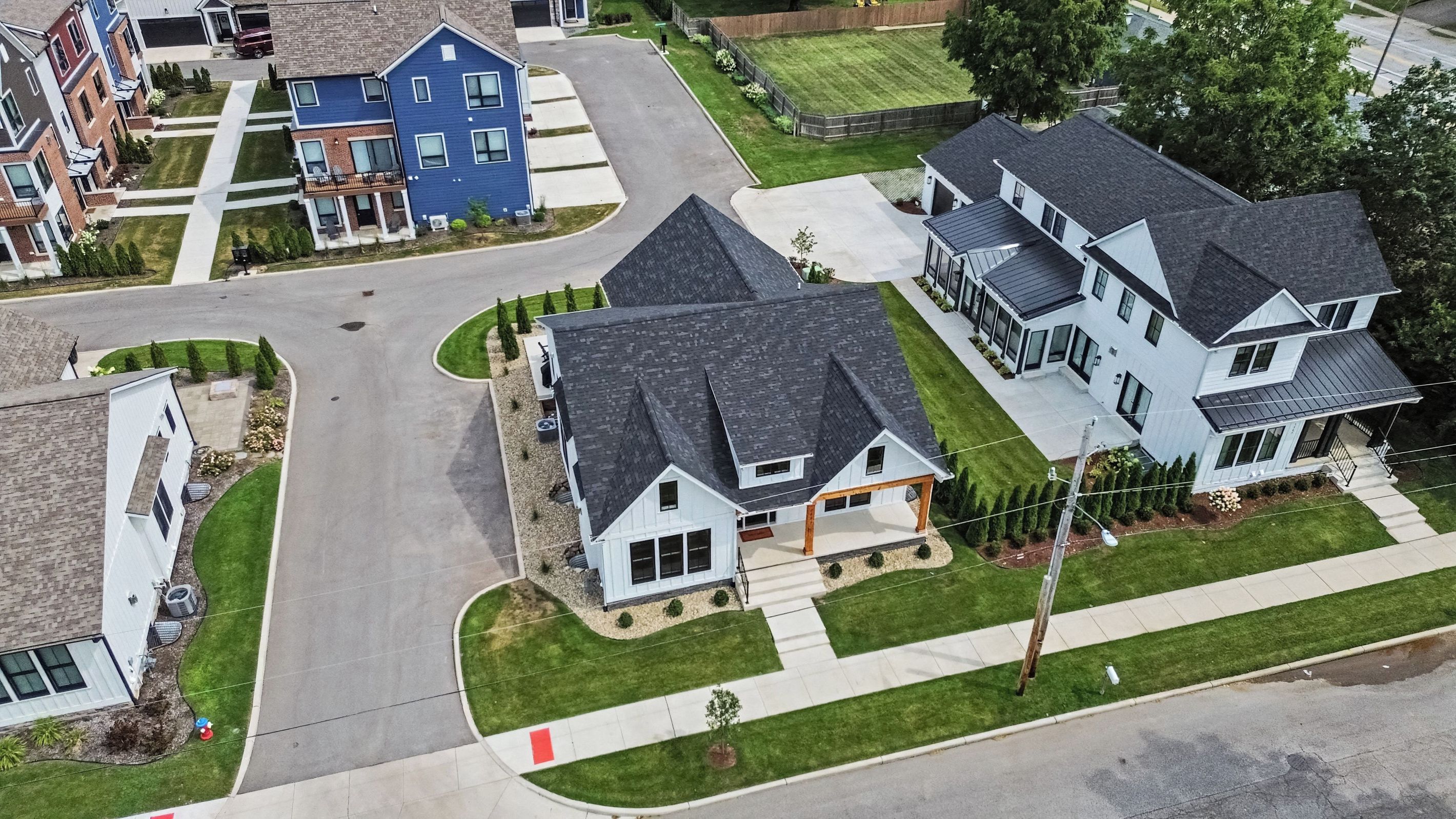 Um bairro residencial com várias casas, uma entrada de automóvel em curva e um gramado bem cuidado.