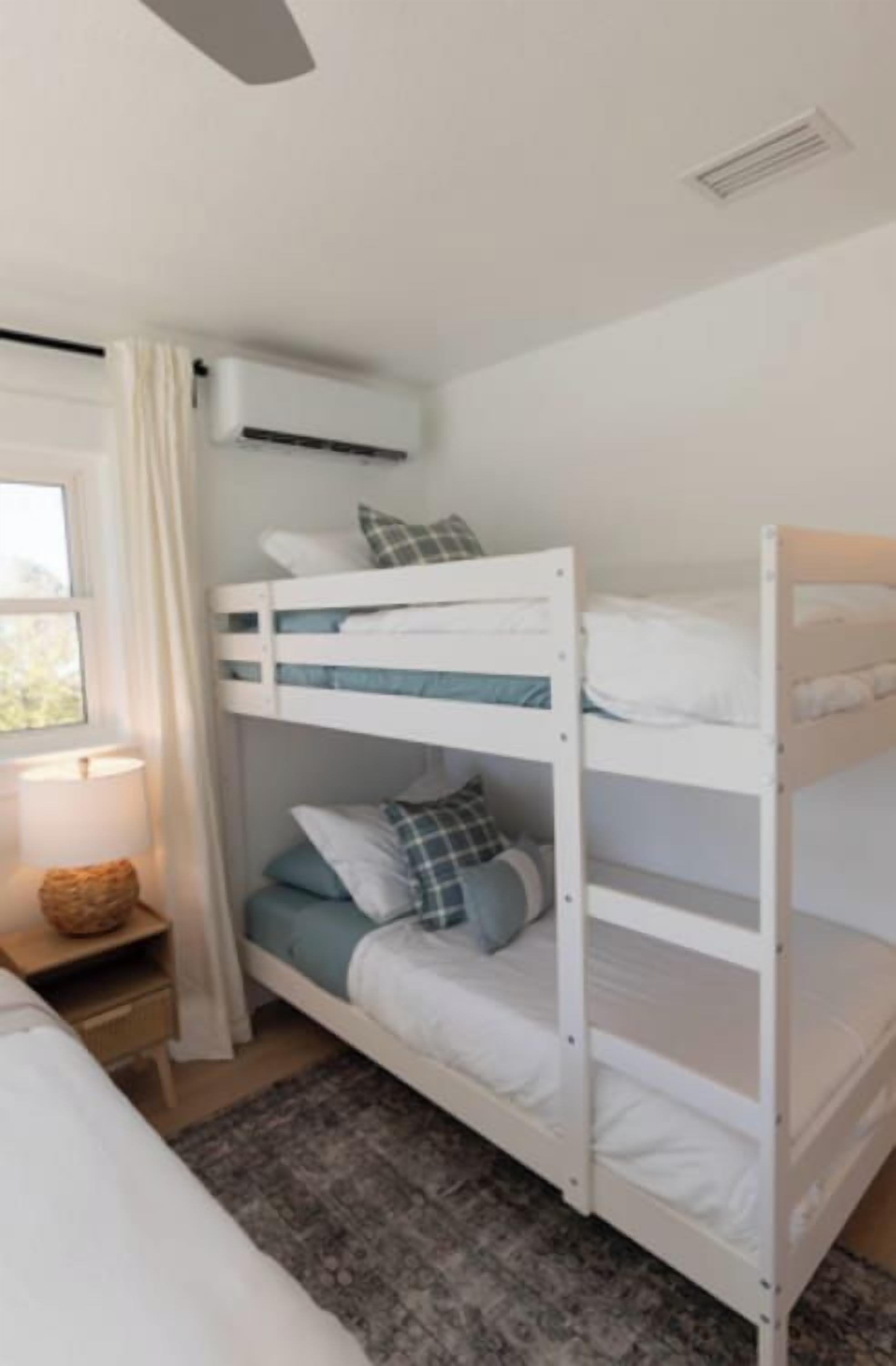 Dormitorio con literas, una mesita de noche y ventilador de techo.