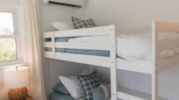 Dormitorio con literas, una mesita de noche y ventilador de techo.