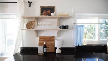 Una cocina con encimera negra, repisas de madera, una botella de vino y un marco de fotos.
