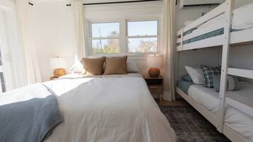 Un dormitorio con una cama individual, una litera, una ventana con cortinas, una lámpara de noche y un aire acondicionado instalado en la pared.