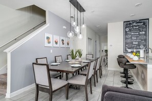 A modern dining area with a long table, chairs, and pendant lighting. - SUNNY 5-bedroom house with AC in charming Davenport (Davenport)
