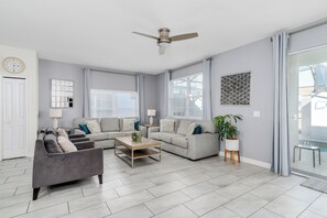 Ein modernes Wohnzimmer mit grauem Sofa, Couchtisch und Deckenventilator.