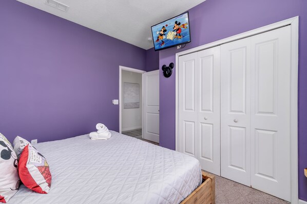 A bedroom with a bed, a television on the wall, and a wardrobe. - SUNNY 5-bedroom house with AC in charming Davenport (Davenport)