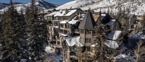 Un complejo turístico en la montaña cubierto de nieve, con varios edificios, incluyendo una imponente torre.