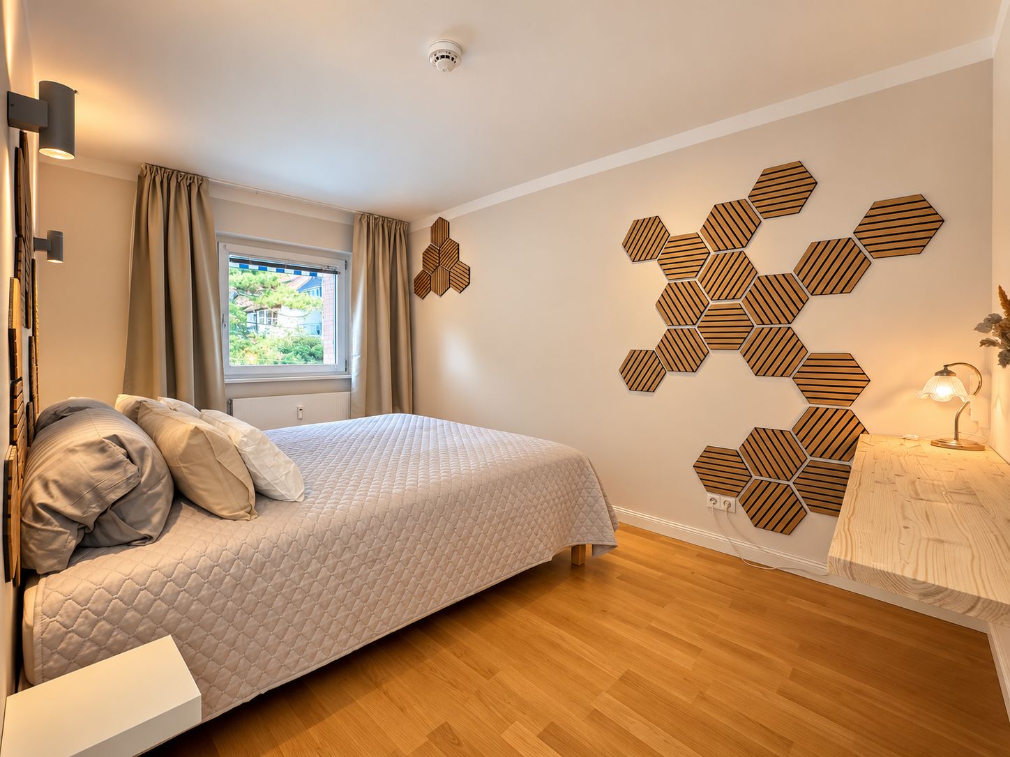 Un dormitorio moderno con cama, suelo de madera, una ventana con cortinas y un patrón hexagonal en la pared.