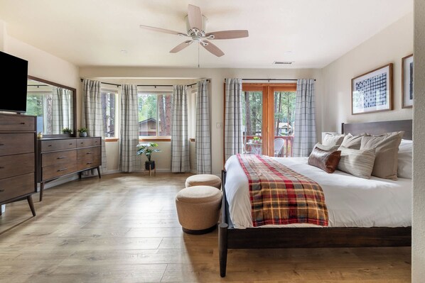 Un dormitorio con cama, cómoda, ventilador de techo y ventana con cortinas.