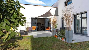 Et moderne hus med terrasse, udendørs møbler og et stort vindue.
