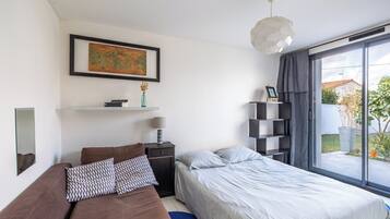Et moderne soveværelse med seng, natbord, lampe, et kort på væggen og udsigt til det fri.